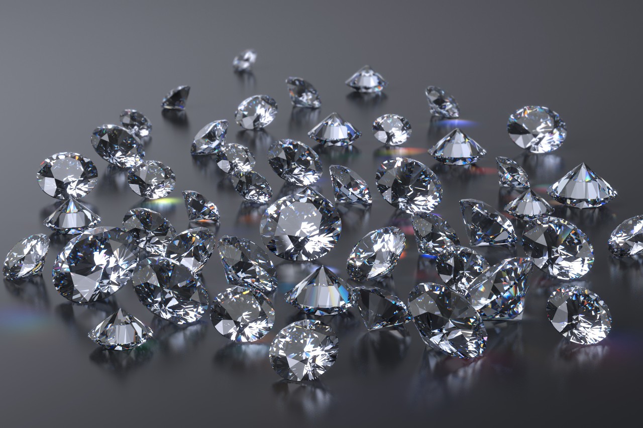 A scattered pile of sparkling diamonds on a sleek gray surface.
