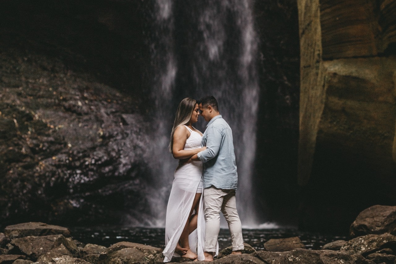 a couple embracing by a waterfall