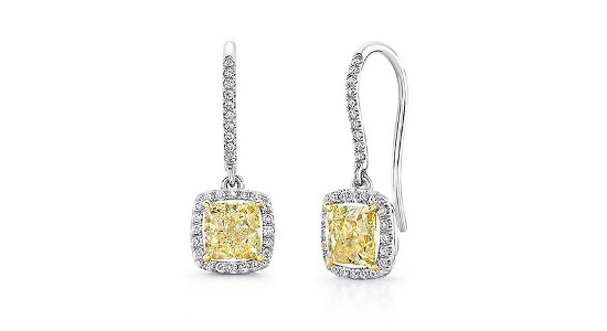 a pair of drop earrings featuring yellow diamonds and a diamond halo