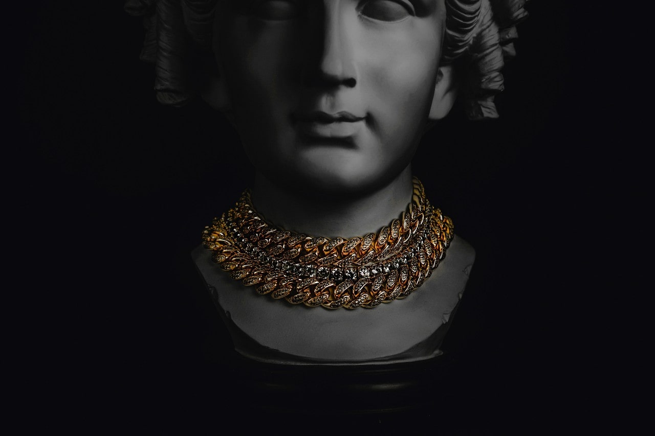 a female bust wearing gold chain necklaces