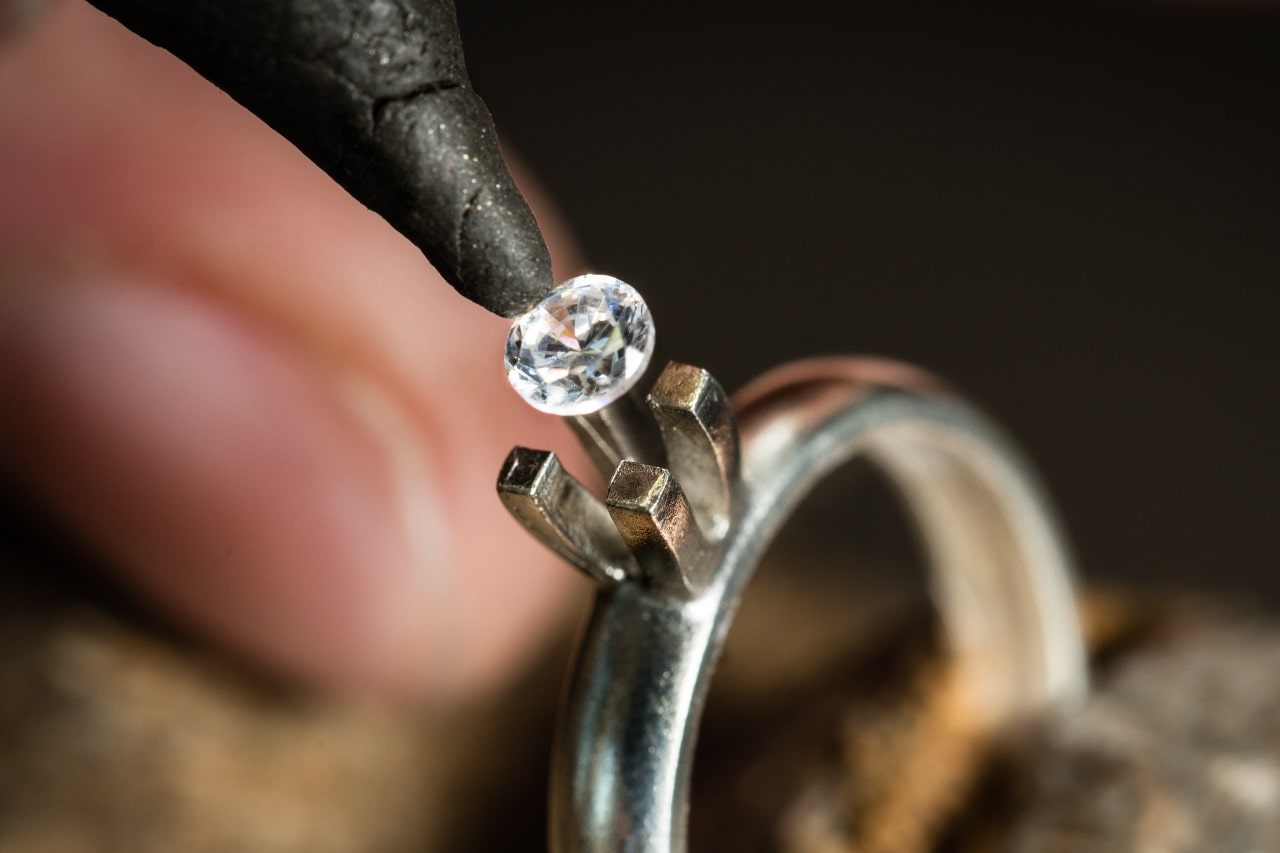 Close up of a jeweler carefully setting a sparkling diamond onto a ring.