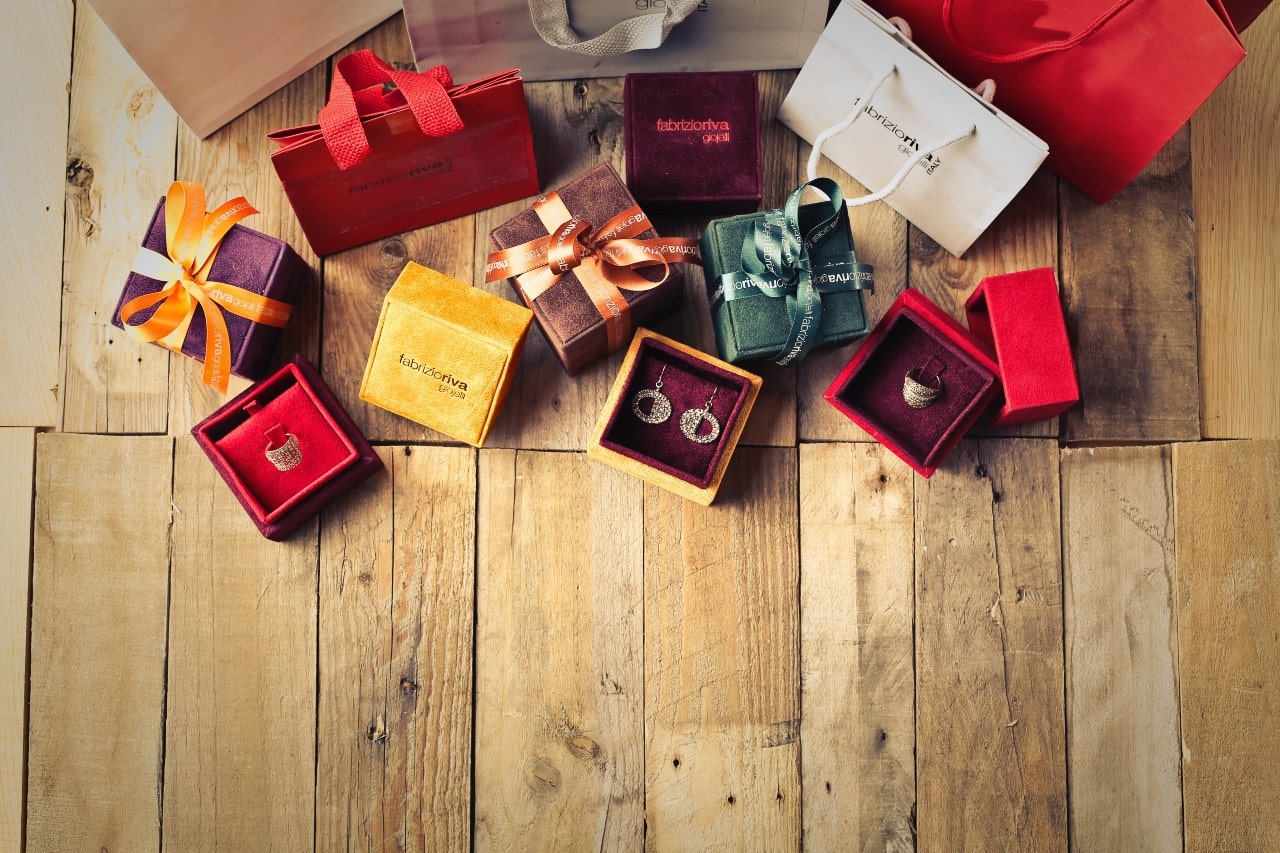 A close up of open jewelry boxes with ribbons all over the wooden surface.