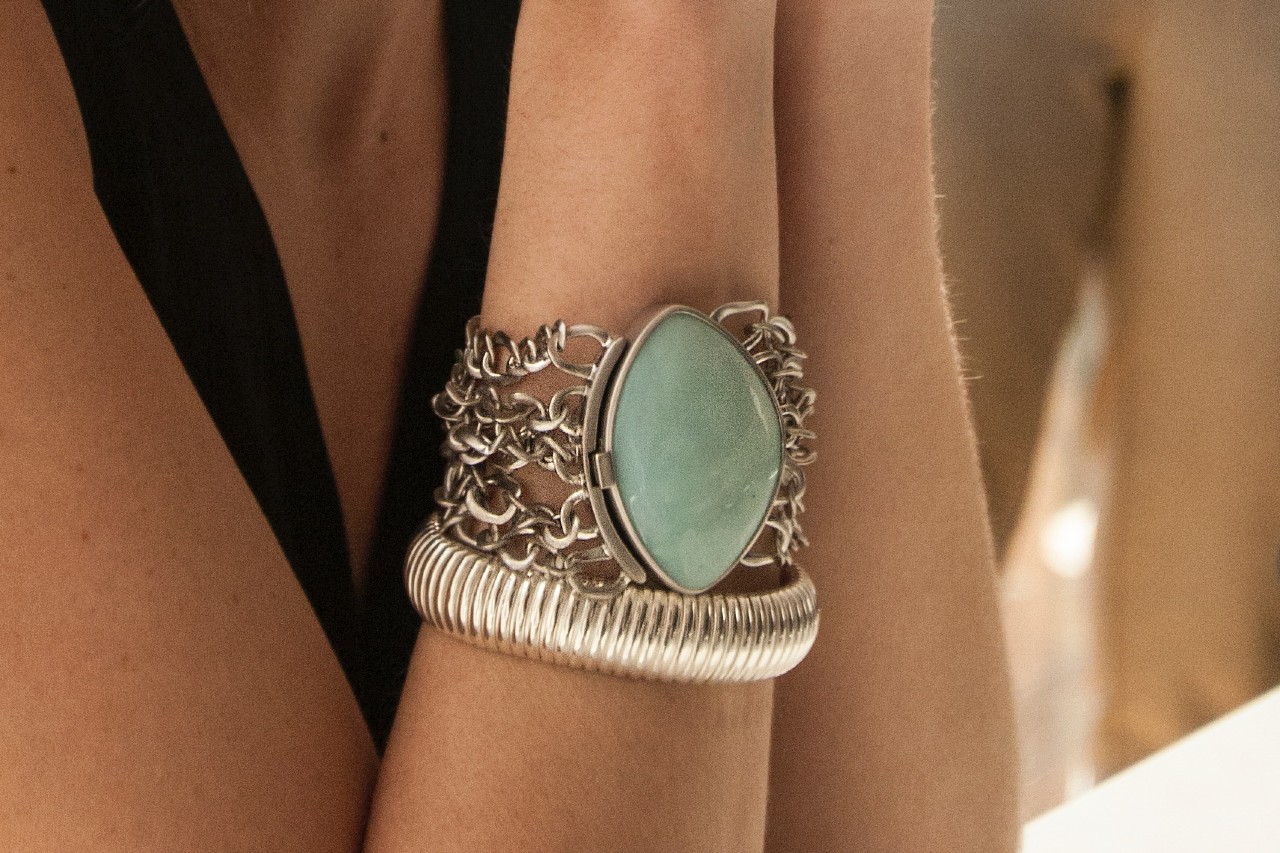 A woman’s wrist with a bangle and a bold turquoise chain bracelet.