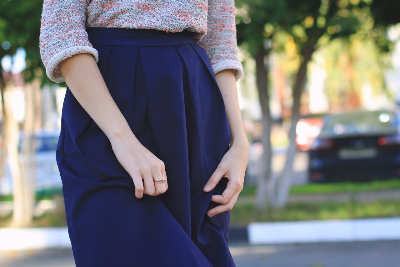 lady’s hands and torso wearing a blue skirt and a luxurious fashion ring