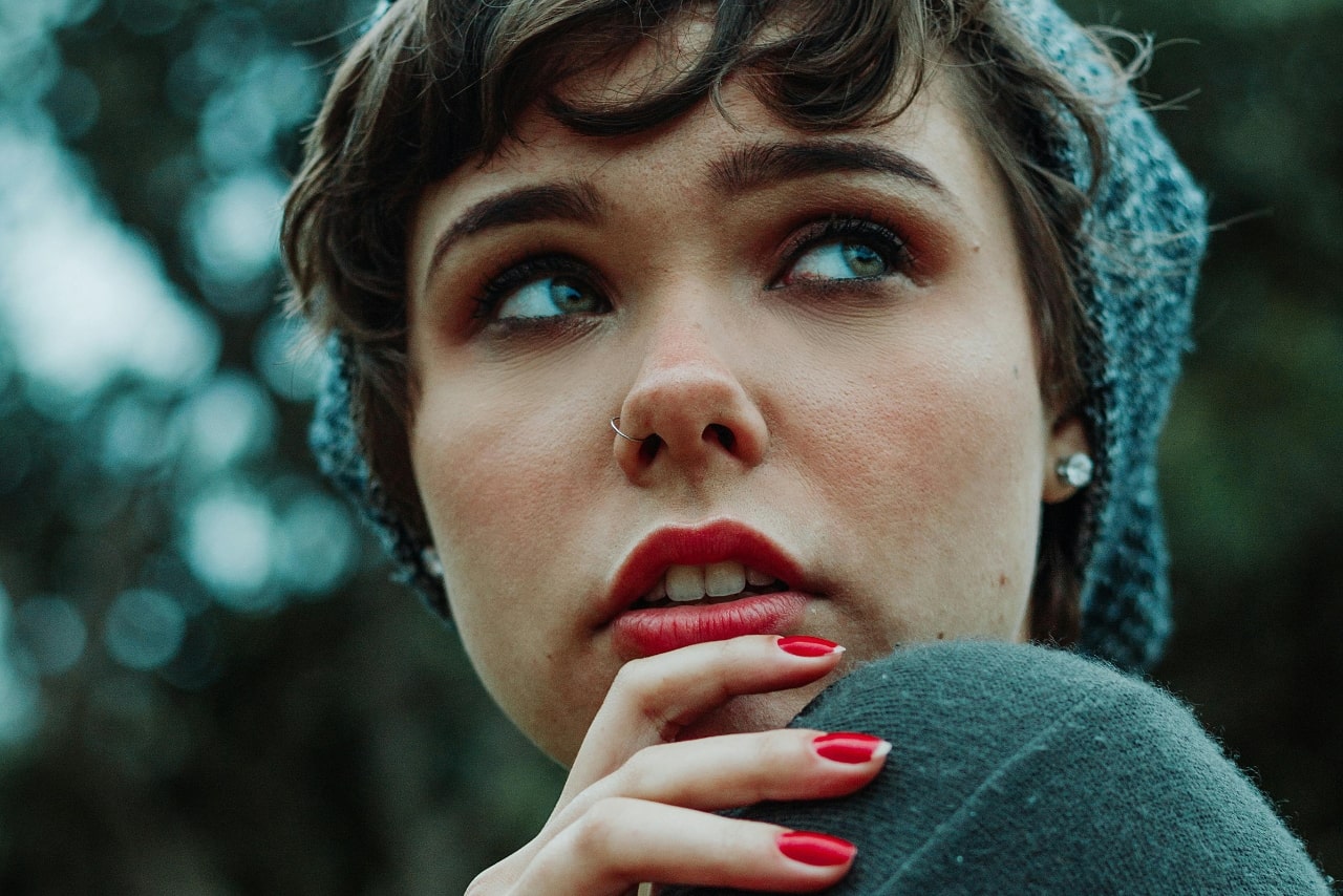 A close-up of a fashionable young woman wearing a pair of large diamond stud earrings.