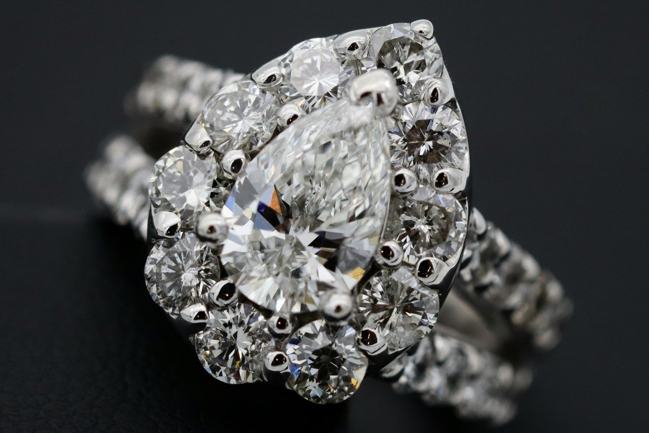 A close-up of a spectacular pear shape engagement ring, fully covered in shimmering diamonds.