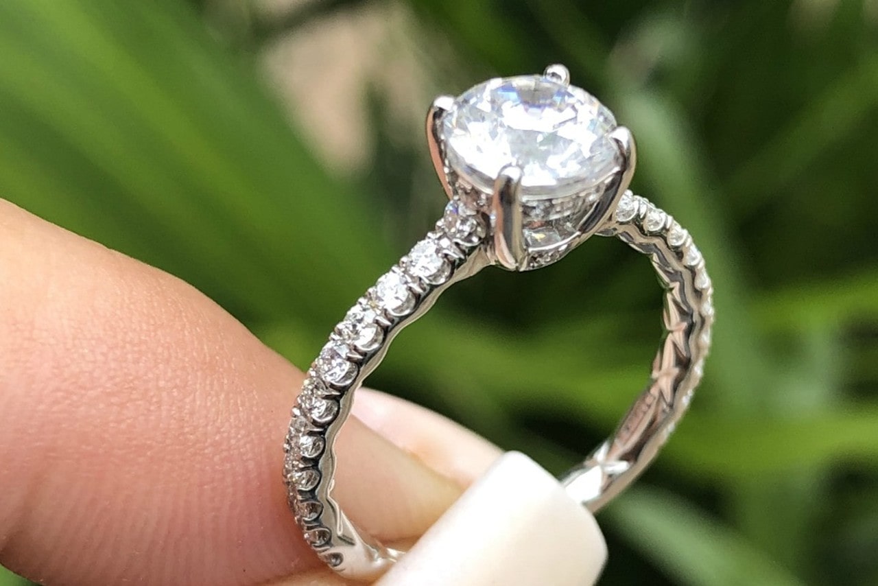 A woman holding a side stone engagement ring outside.