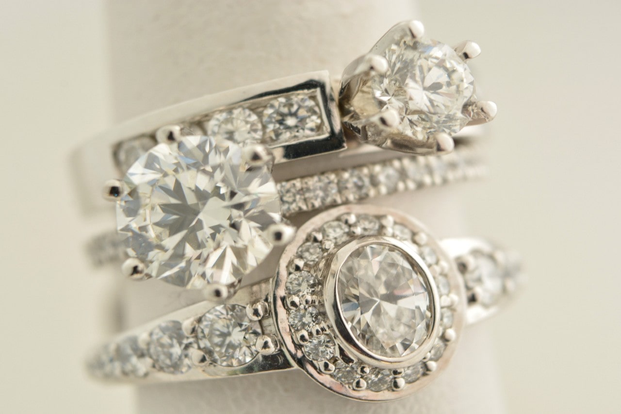 Three side stone engagement rings on a ring display.