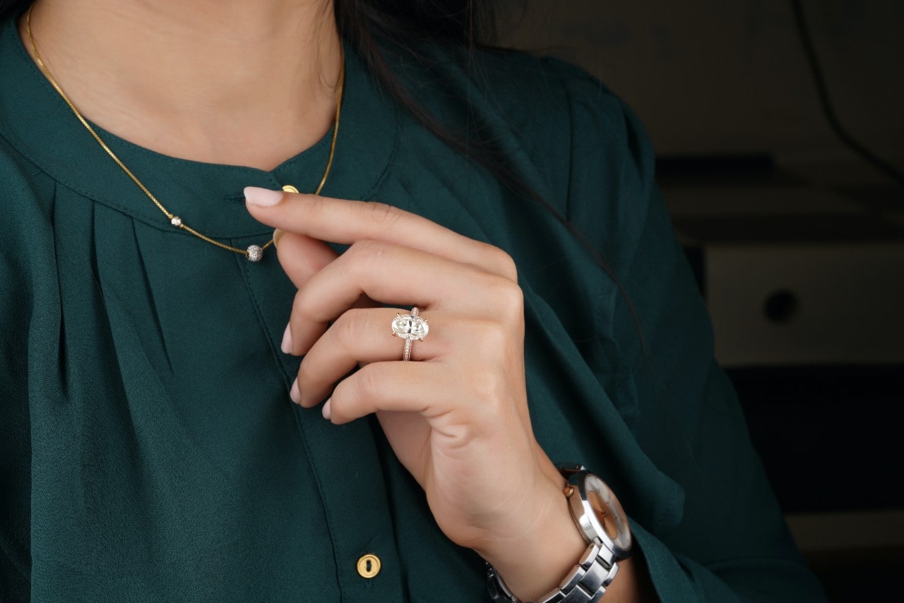 A woman in a green blouse wearing a large diamond solitaire engagement ring