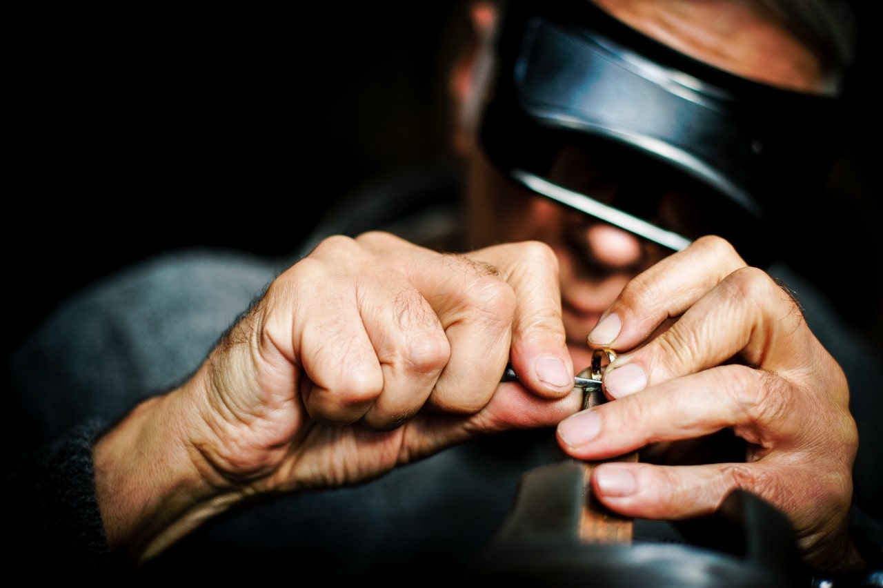 A close-up of a jeweler’s hands as he maintains a yellow gold band.